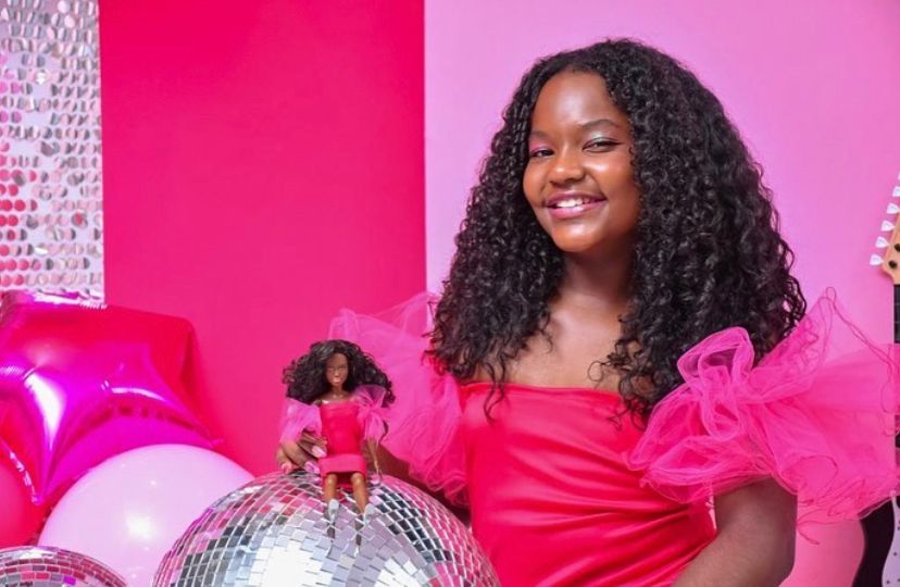 Foto mostra menina segurando barbie negra