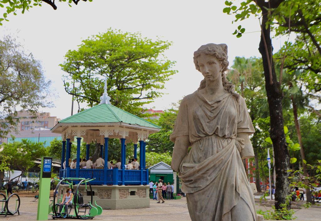 Em primeiro plano, estátua de mulher. Ao fundo, o coreto da praça Jardim do Méier.