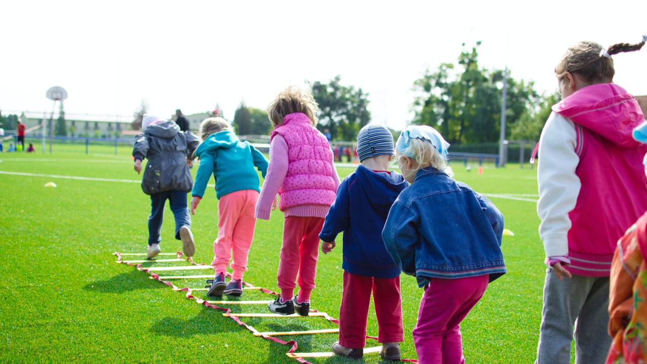 Crianças ao ar livre realizando atividade física em um campo.