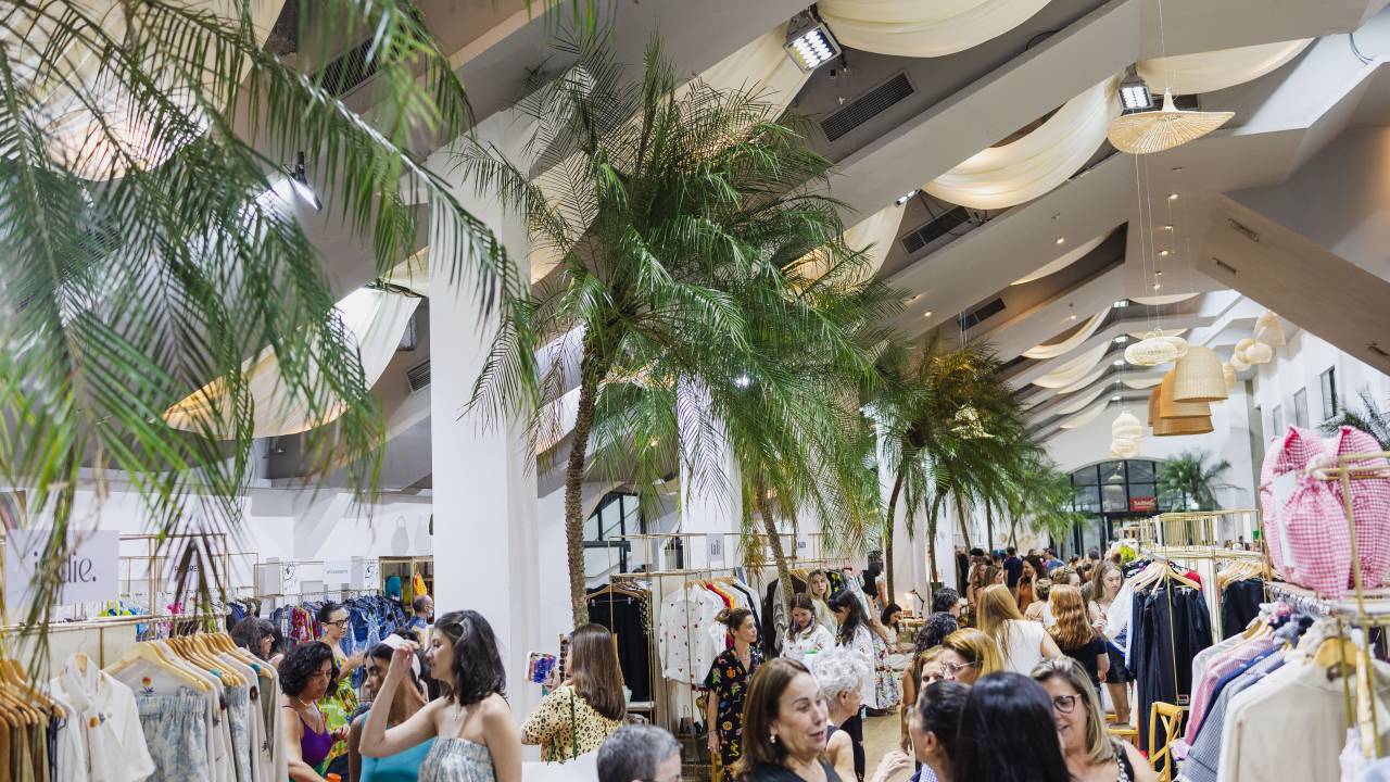 Público da feira em um espaço com teto branco e plantas pendentes