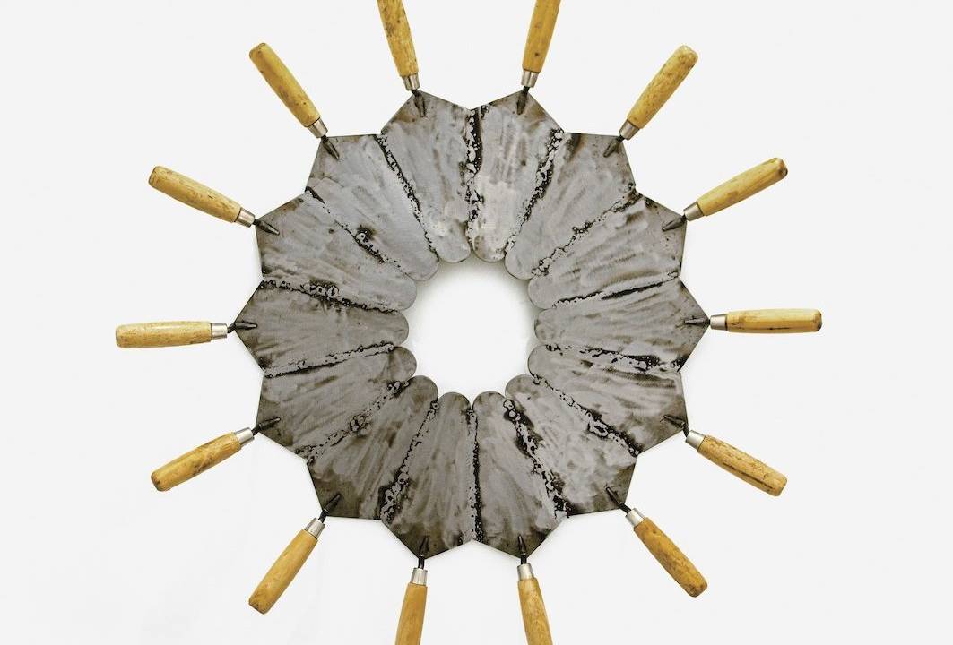 Objeto circular formado por colheres de pedreiro com o cabo para fora