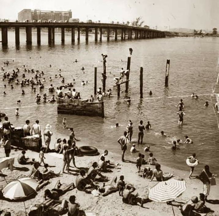 Foto de pessoas tomando banho de mar na Praia do Galeão, década de 1960