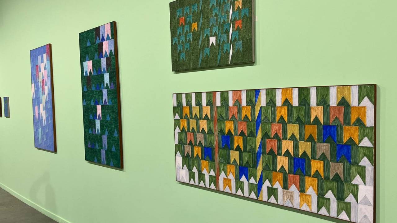 Parede verde-claro com quatro quadros de Volpi com bandeirinhas coloridas de festa junina