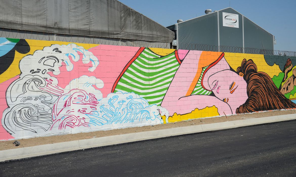 Muro com um grafite de uma mulher branca e de cabelos castanhos deitada