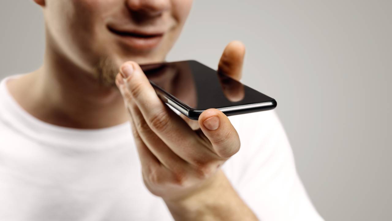 Homem com o celular na mão grava uma mensagem de voz.