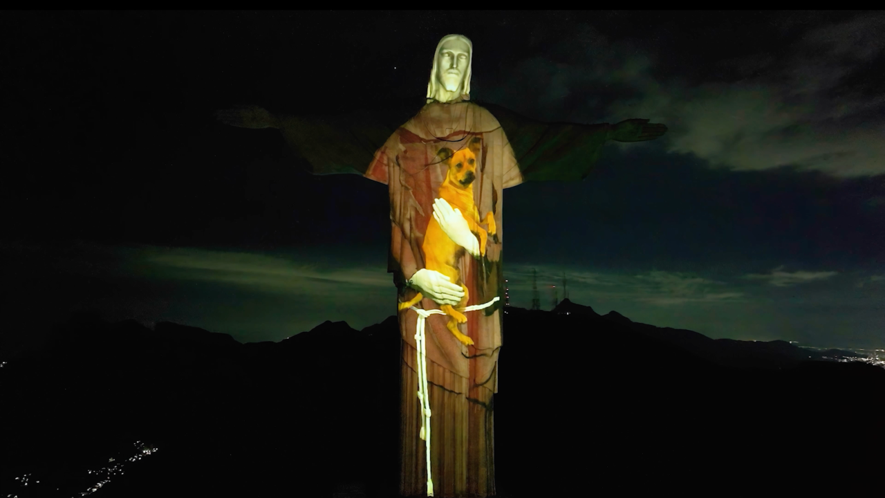 Estátua do Cristo com projeção estilo mapping que simula um abraço