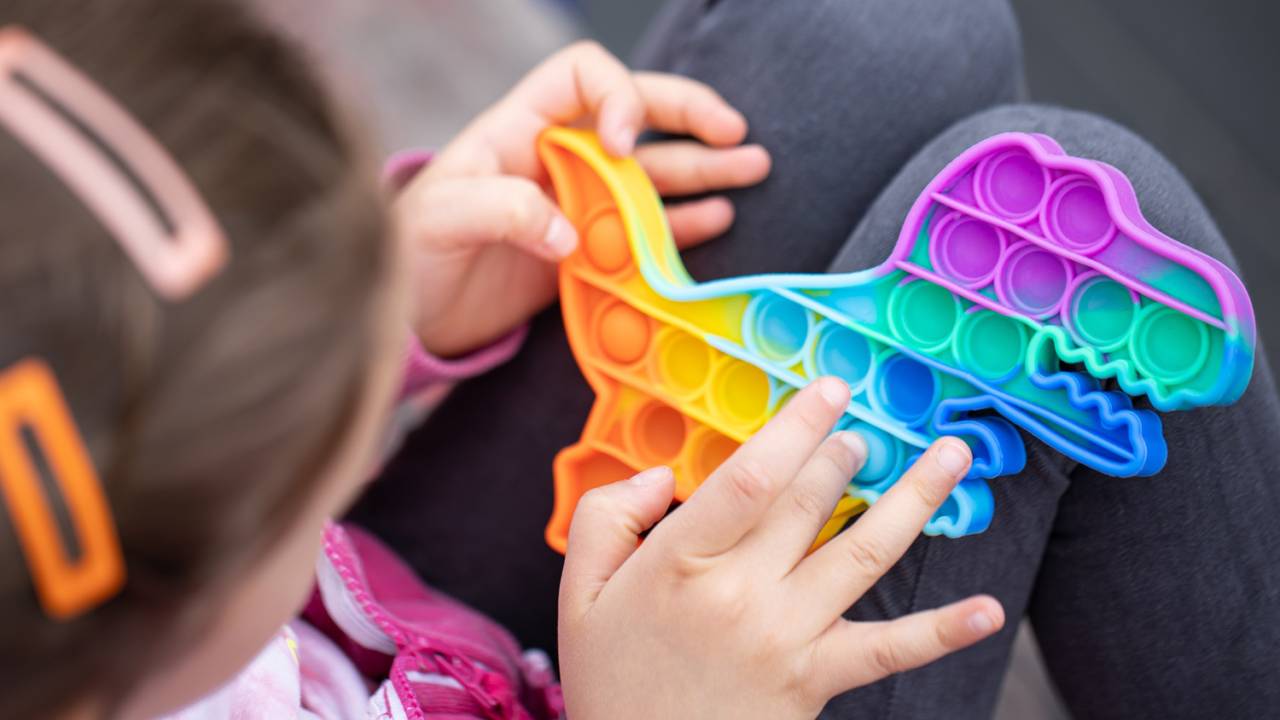 Criança segura brinquedo nas cores do autismo.