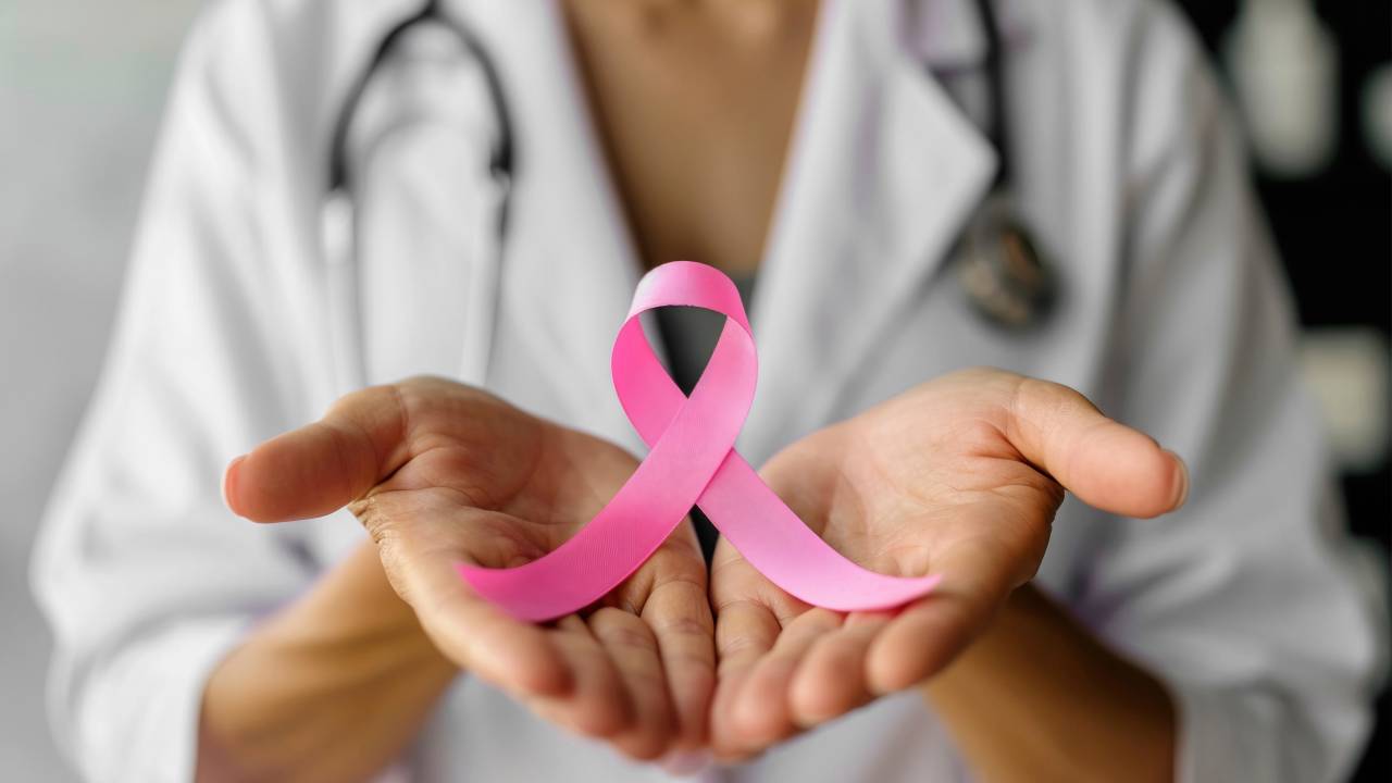 Pessoa segura nas mãos o símbolo da campanha contra o câncer.