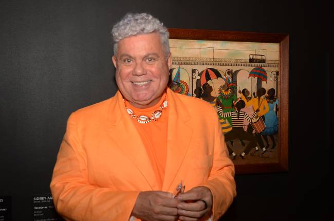 Milton Cunha com a tela de Heitor dos Prazeres do fundo, inspirada no carnaval