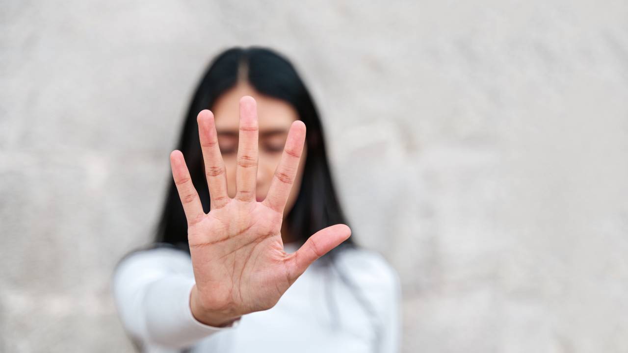 Mulher levanta a mão para dizer chega. Campanha para acabar com a violência contra as mulheres. Mulher latina com a mão cobrindo o rosto