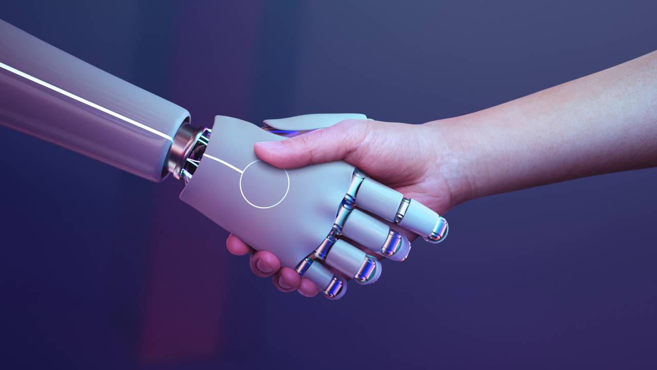 Mão humana cumprimenta a mão de um robô.