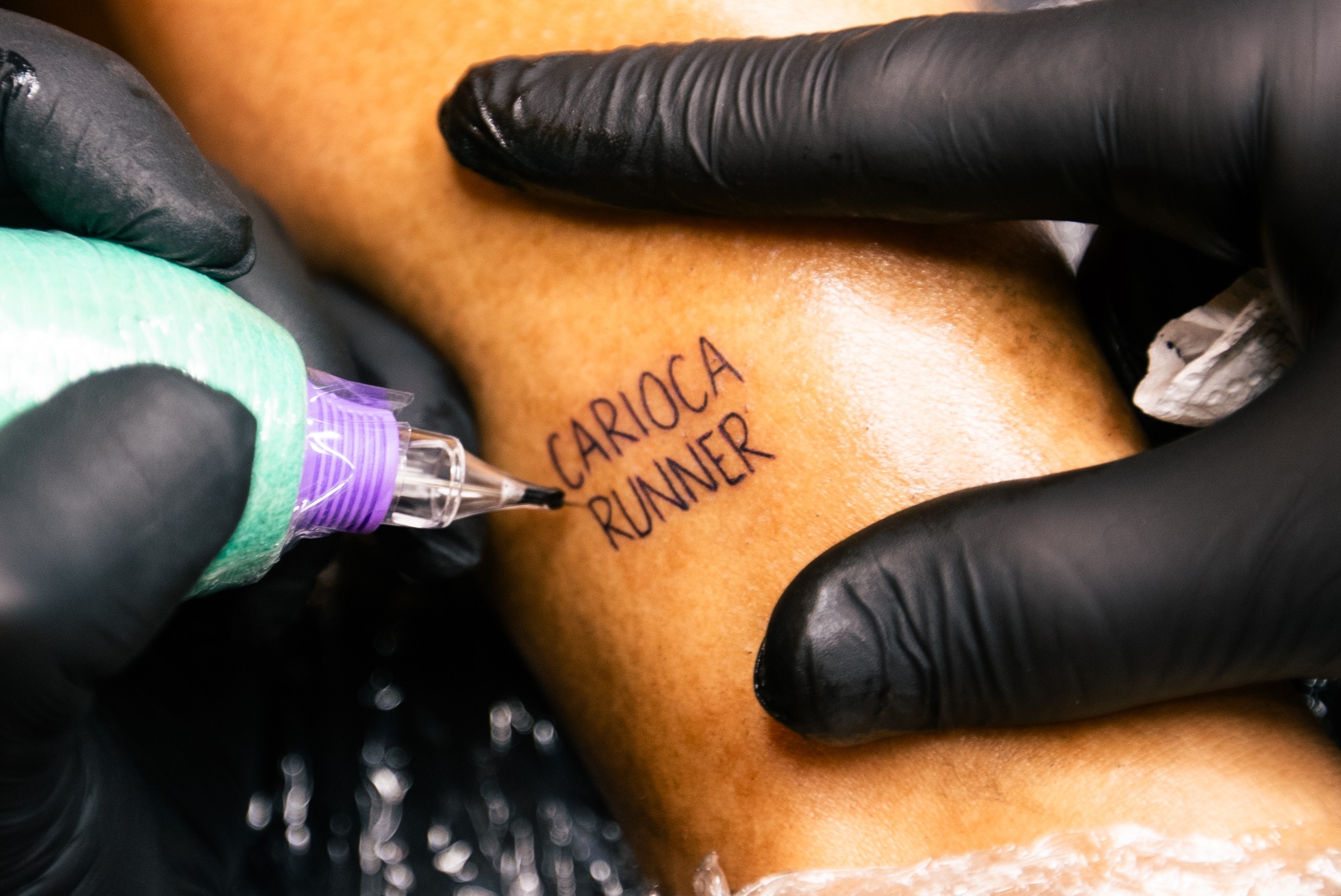 Tatuador com luvas pretas tatuando 