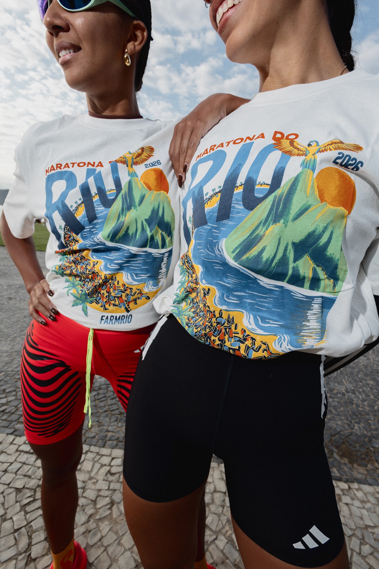 Duas mulheres sorrindo, usando camisetas brancas com estampa colorida da 