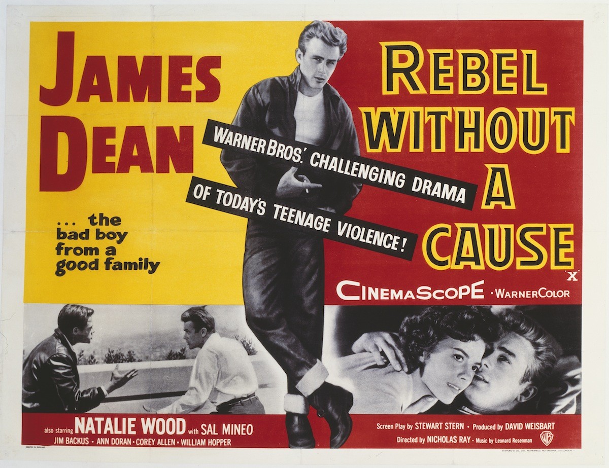 Pôster do filme Rebel Without a Cause com James Dean em destaque, vestindo jaqueta e calça jeans, olhando para baixo. Abaixo, duas cenas em preto e branco: uma com dois homens conversando e outra com um casal abraçado. O título Rebel Without a Cause está em amarelo e vermelho, e James Dean em vermelho sobre fundo amarelo. Há textos promocionais como Warner Bros. Challenging Drama of Todays Teenage Violence!